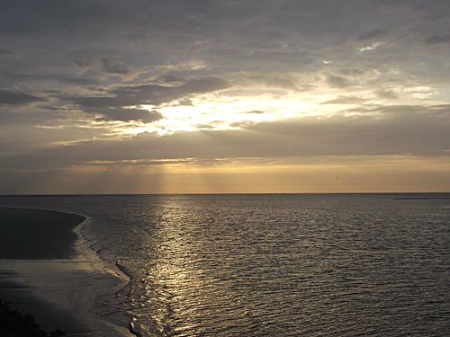 Sunbeams break over a silver sea